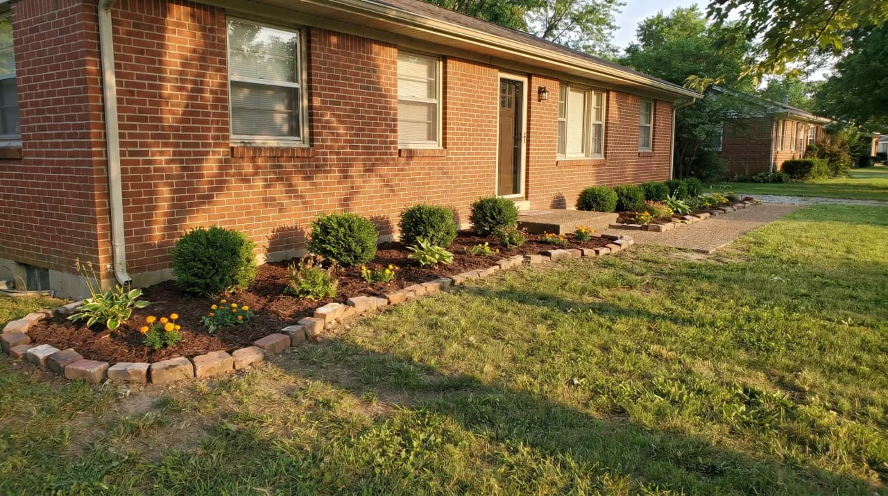 Brick ranch with simple mulch border bed, rock edging and small flowering shrubs