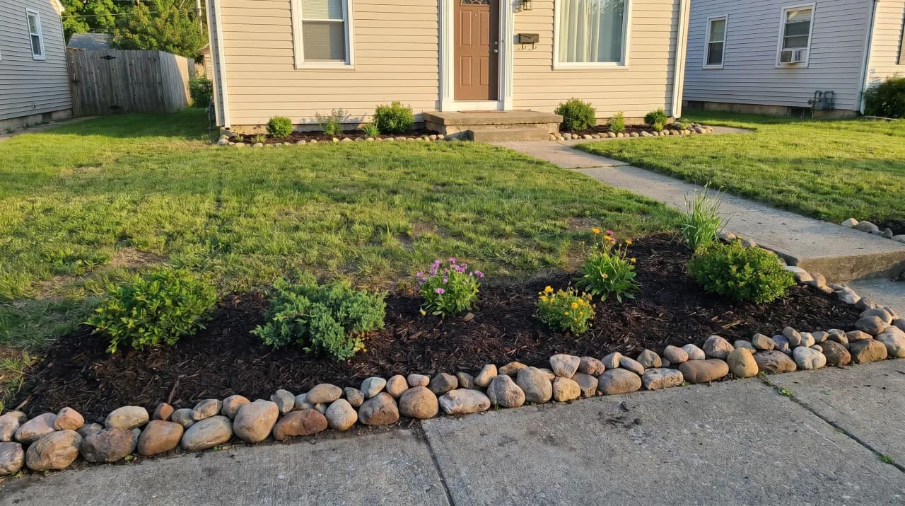 Simple ranch with a small rock-edged island mulch bed, a few small shrubs and a tidy lawn