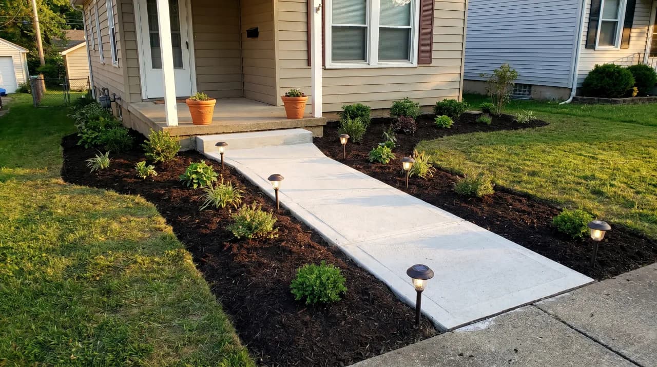 Ranch home with wide concrete path, clean mulch beds, low shrubs and solar path lights