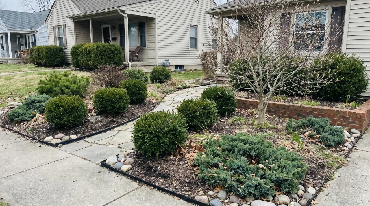 Ranch home with simple mulch beds, round clipped boxwood shrubs and rock border