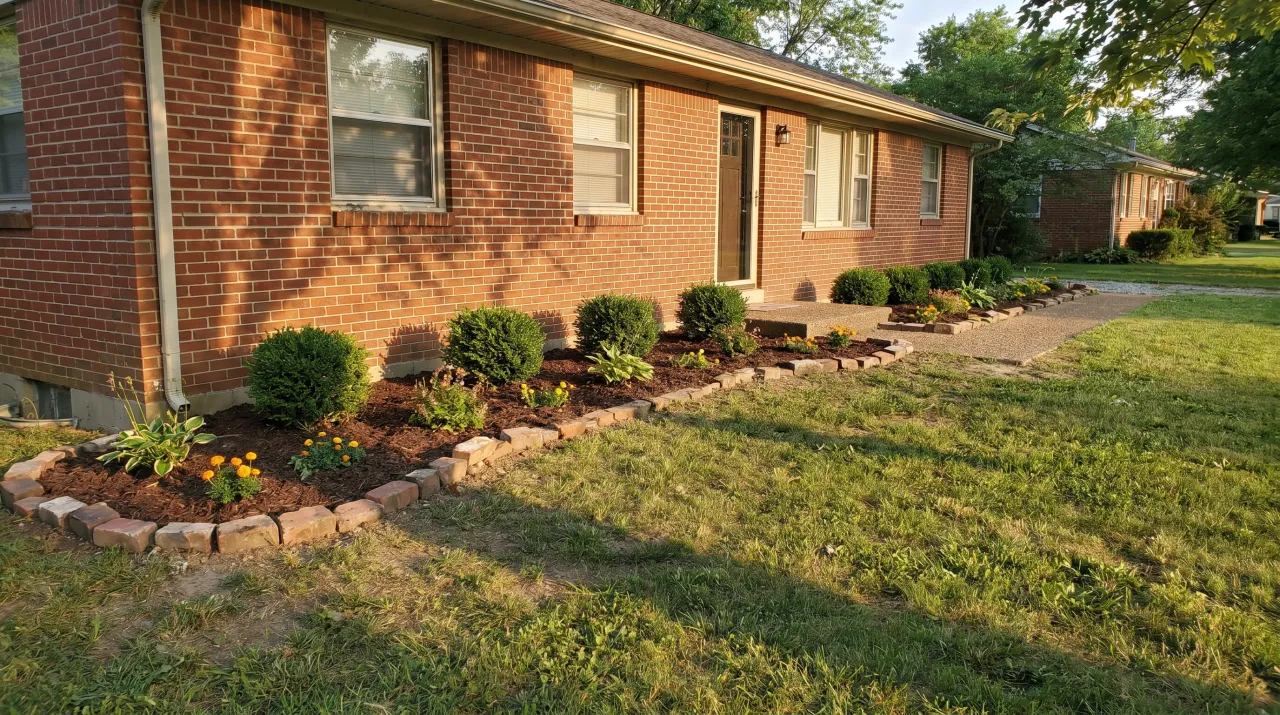 Brick ranch with simple mulch border bed, rock edging and small flowering shrubs